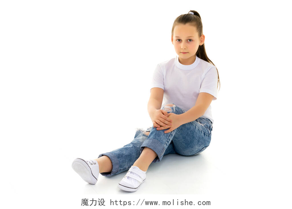 坐在白色背景上的小女孩一个小女孩穿着干净的白色T恤坐在地板上.